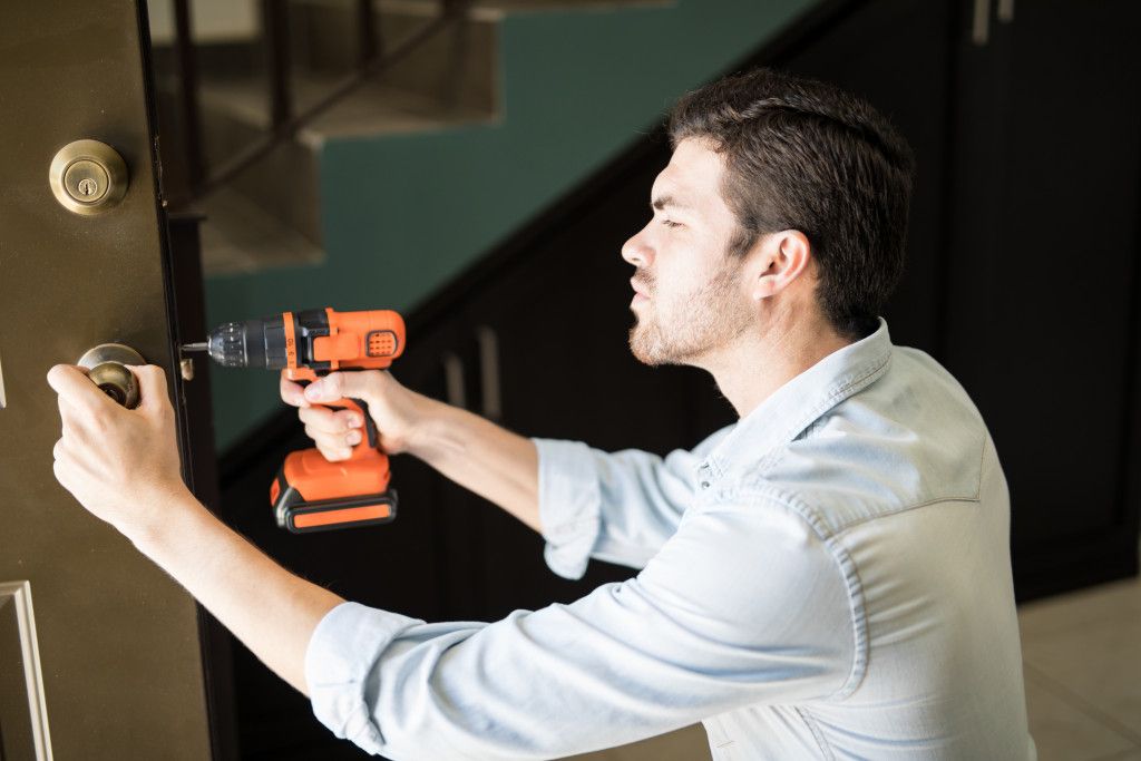 profile-view-of-an-attractive-handyman-using-a-power-drill-to-fix-a-door-knob-in-a-house.jpg